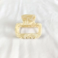 Detail view of a cream marble acetate hair claw clip with a hollow rectangular design - Off White