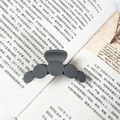 Matte dark grey claw clip featuring five circular geometric patterns on an open book - Gray