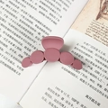 Detail of a matte mauve purple claw clip with round design on an open book - Brick Red