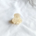 Macro detail of a cream acetate hair claw clip with pearl texture on white fabric - Milky White