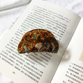 Dettaglio molletta per capelli tartarugata con trama ambra e blu su un libro d'epoca - Floreale Caffè