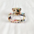 Detail of a rectangular acetate hair claw with colorful marble textures on white fabric - Multicolor