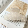 Detail of 9cm iridescent marble hair claw clip resting on an artistic book page - 9cm / Mermaid White