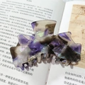 Elegante pinza de pelo en acetato de mármol morado sobre fondo de un libro antiguo - Serie Café Púrpura