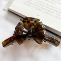 Pinza de pelo con lazo de acetato y textura jaspeada azul y marrón sobre libro - Marrón Ámbar