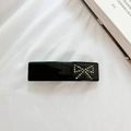Elegante pinza de pelo negra con lazo de diamantes de imitación sobre tela blanca - Negro