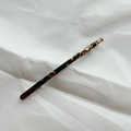 Macro shot of a long tortoiseshell acetate hair clip with metal spring on white fabric - Small Black Floral