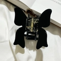 Détail de la pince à cheveux papillon en acétate noir brillant sur tissu blanc doux - Noir