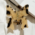 Détail d'une pince à cheveux papillon avec motif écaille de tortue sur fond de tissu - Écaille de Tortue Claire