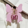 Close-up of a pink butterfly hair claw clip with golden spring on a white fabric background - Pink