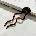 Detailopname van de golvende U-vormige schildpad haarpin van acetaat op een boek - Rode Luipaardprint