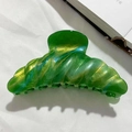 Detailed close-up of large emerald green marble shark hair claw with gold shimmer finish - Green
