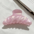 Macro shot of pink pearlescent hair claw clip with shell texture on white fabric - Pink