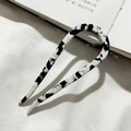 Detail van U-vormige acetaat haarspeld met marmerpatroon op een witte stoffen achtergrond - Zwart en Wit Gespikkeld
