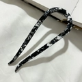 Macro shot of marble textured acetate hair pin resting on a white fabric surface - Black Floral