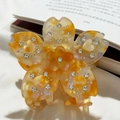 Détail d'une pince à cheveux fleur en acétate ambré avec strass et charms en cœur - Fleur Orange