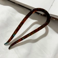 Close-up of tortoise shell pattern acetate U-shaped hair pin for elegant buns - Amber Brown
