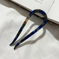 Macro detail of tortoiseshell U-shaped hair pin in deep blue acetate on white fabric - Blue Floral