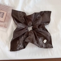 Close-up of a dark brown paisley scrunchie with a white Botani brand tag on fabric - Coffee Paisley Scarf Style
