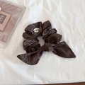 Macro view of dark brown paisley print hair scrunchie with bow and brand charm detail - Coffee Paisley Bowknot Style