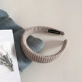 Detalle de una diadema de punto beige con etiqueta de Handmade cosida en el interior - Albaricoque