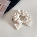 Detalle del coletero de lazo en terciopelo blanco con textura plisada y etiqueta elegante - Blanco Roto