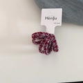 Detail van rood en grijs haarelastiek met houndstooth-patroon op witte kaart en denim - Hahnentritt Stijl