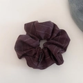 Macro view of burgundy striped fabric scrunchie with a black brand label detail - Dark Red Scrunchie