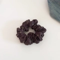 Detailopname van een donkerpaarse scrunchie met bloemenprint op witte en denim achtergrond - Koffie/Bruin