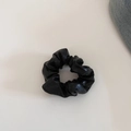 Close-up of black faux leather scrunchie with glossy texture and pleated details - Black Small