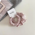 Detail of pink satin scrunchie with soft pleats and a branded paper hang tag - Simple Style