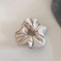 Detailed view of a creamy white faux leather scrunchie with soft pleats and glossy texture - Beige Large