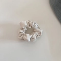 Close-up of cream white faux leather scrunchie with textured pleated folds on a beige surface - Beige Small