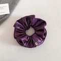 Détail du chouchou en satin plissé violet foncé avec un petit charme en métal doré - Violet