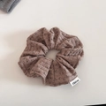 Nahaufnahme von braunem Strick-Haargummi mit Blumenmuster und weißem Markenetikett - Kaffee/Braun