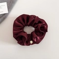 Détail du chouchou en satin bordeaux avec plis superposés et médaillon rond en métal doré - Rouge Vin