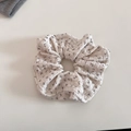 Detailansicht eines cremefarbenen Haargummis mit Blumenmuster und weichem Stoffgewebe - Off-White