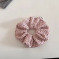 Detailaufnahme von rosa geblümtem Strick-Scrunchie mit weicher Rippstruktur und Logo - Rosa