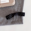 Detalle de pinza para el pelo con lazo de lunares blancos y negros sobre tela gris - Negro