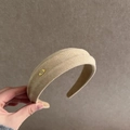 Primer plano de diadema de ante beige con textura y etiqueta metálica dorada Hand Made - Albaricoque