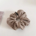 Close-up of oatmeal knit scrunchie with soft ribbed texture and a black brand label - Apricot