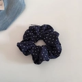 Gros plan d'un chouchou bleu marine à pois blancs avec étiquette tissée sur fond blanc pur - Pois Bleu Marine