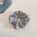 Gros plan sur un chouchou floral gris avec texture côtelée et étiquette de marque - Floral Gris