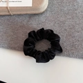 Detail of premium black velvet scrunchie with soft satin luster on a grey fabric background - Black Velvet Style / Black