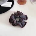 Détail d'un chouchou en maille grise avec bordure marron contrastée sur surface blanche - Gris foncé