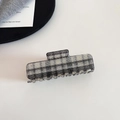 Macro view of checkered acetate hair claw clip showing plaid pattern and spring detail - Black Plaid