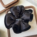 Close-up of black satin scrunchie with velvet trim displayed on a linen tray - Black