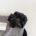 Dettaglio dell'elastico per capelli in tessuto grigio antracite con etichetta a fiocco - Elastico Grigio Scuro