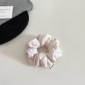 Detail shot of a cream knit scrunchie featuring chunky cable knit texture and brand label - Small / White