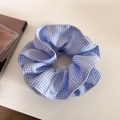 Détail d'un chouchou à carreaux vichy bleu et blanc sur fond esthétique minimaliste - Bleu